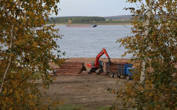 a crane is working on a pile of logs